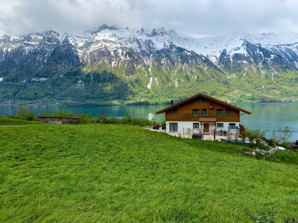 white and brown house near green grass field and mountain during daytime